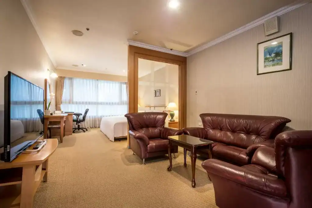 典雅套房設有皮質沙發與書桌區，空間寬敞明亮，適合休憩與辦公