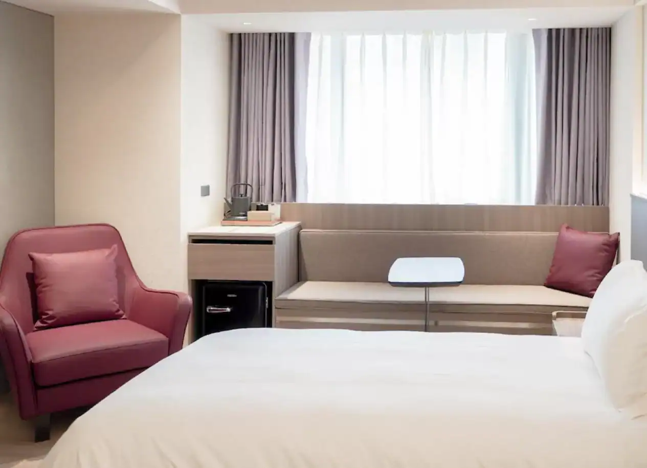 現代簡約客房配備紅色扶手椅與柔和採光。